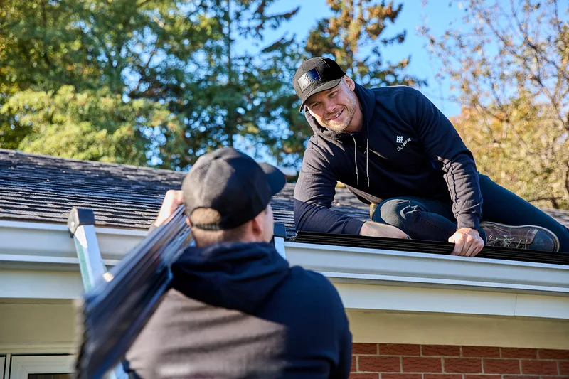 Installer carrying a new seamless gutter up a ladder